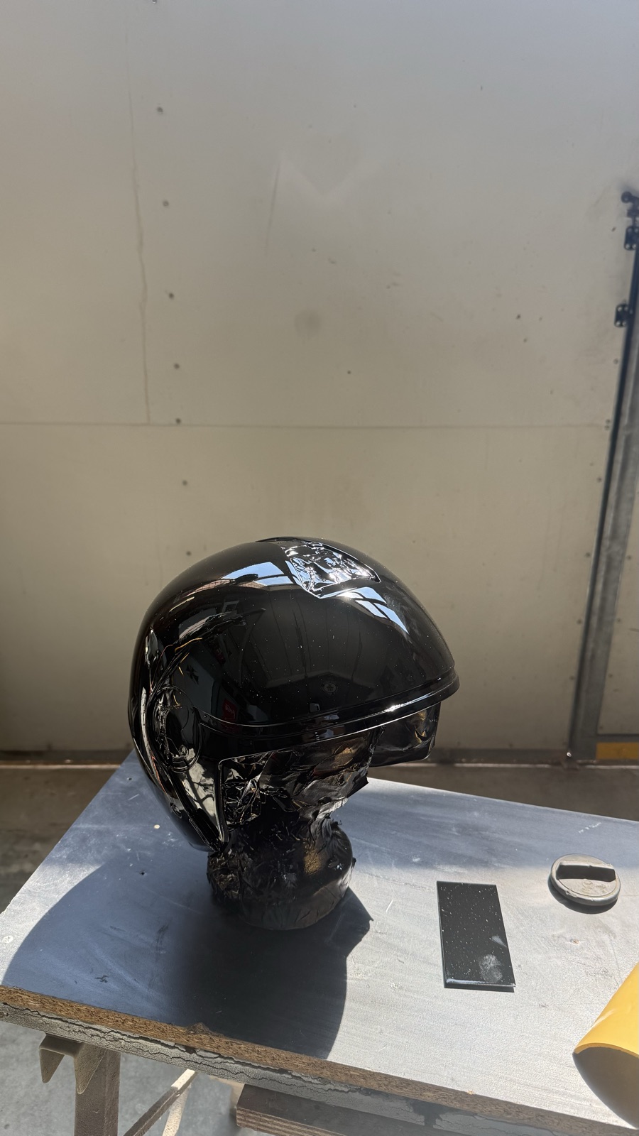 Dettaglio del casco nero lucido con visiera, riflessi a specchio