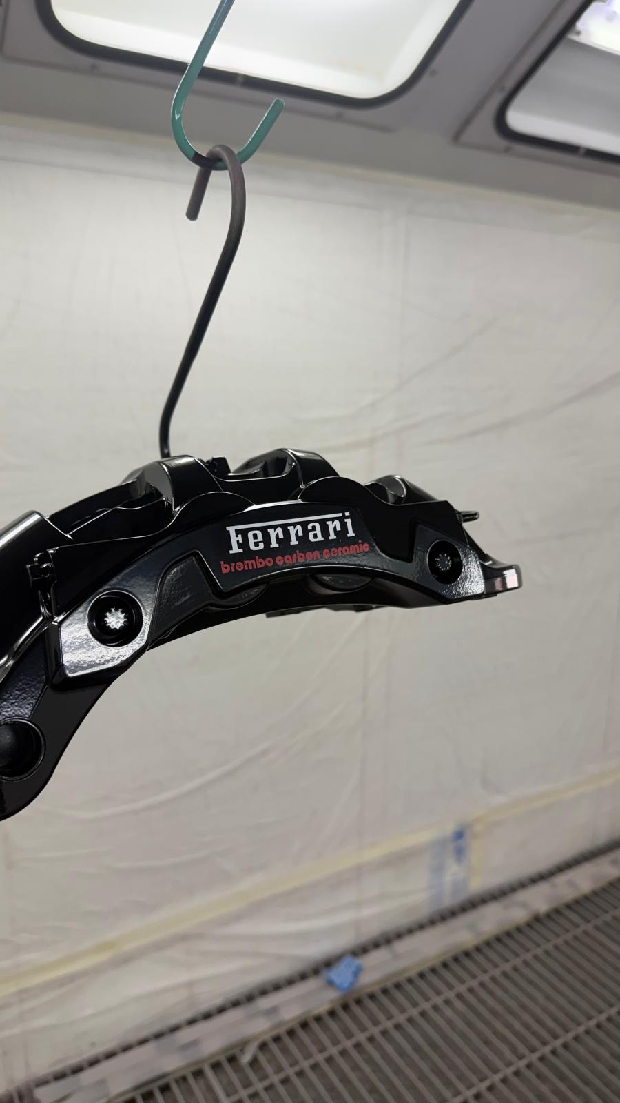 Pinza Ferrari nera appesa ad asciugare in cabina di verniciatura